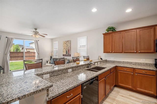 kitchen featuring light wood-type flooring, dishwasher, light stone counters, ceiling fan, and sink