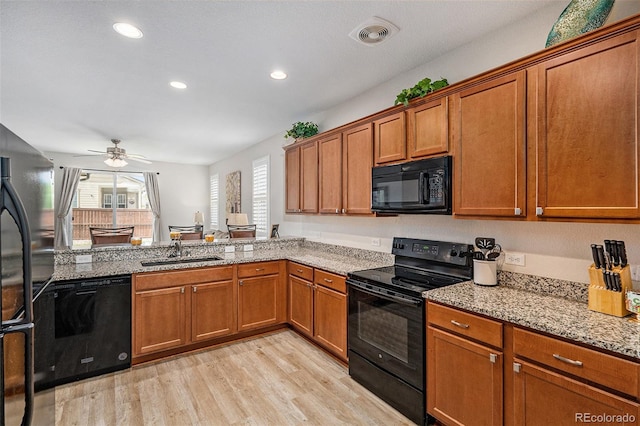 kitchen featuring sink, light stone counters, light wood-type flooring, ceiling fan, and black appliances