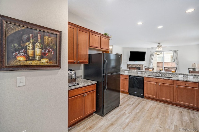 kitchen featuring light hardwood / wood-style flooring, black appliances, light stone counters, ceiling fan, and sink