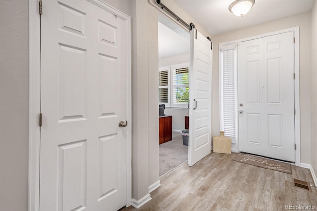 entrance foyer with a barn door and light hardwood / wood-style floors