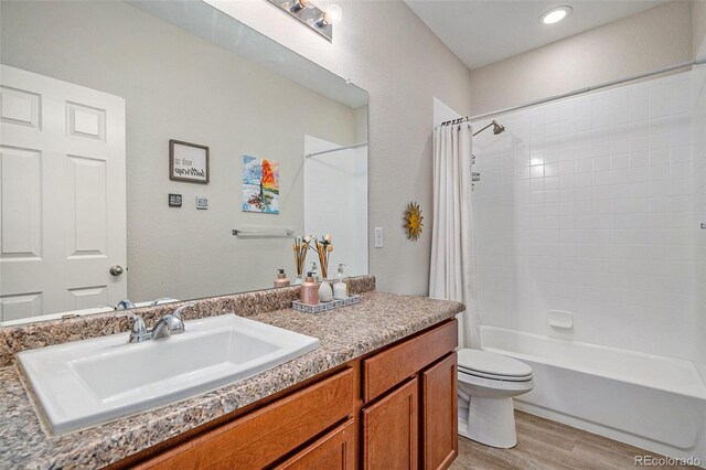 full bathroom with hardwood / wood-style floors, shower / tub combo with curtain, vanity, and toilet