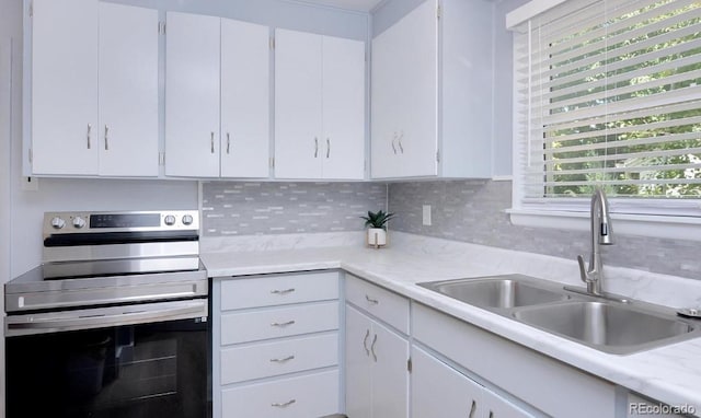 kitchen featuring stainless steel range with electric stovetop, sink, white cabinetry, and tasteful backsplash