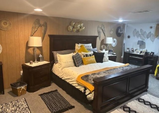 bedroom with light carpet and wooden walls