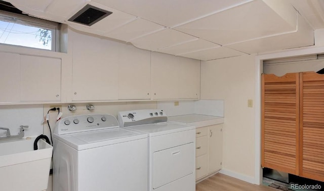 laundry room featuring cabinets, washing machine and dryer, sink, and light hardwood / wood-style floors