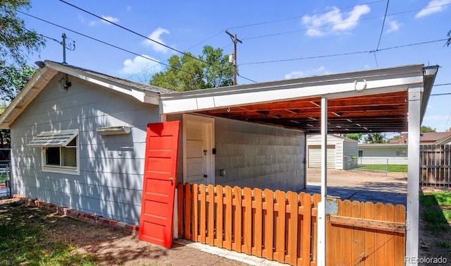 view of outbuilding featuring a carport, an outbuilding, and fence