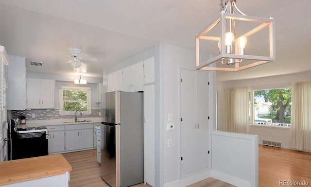 kitchen with visible vents, a sink, freestanding refrigerator, and gas stove