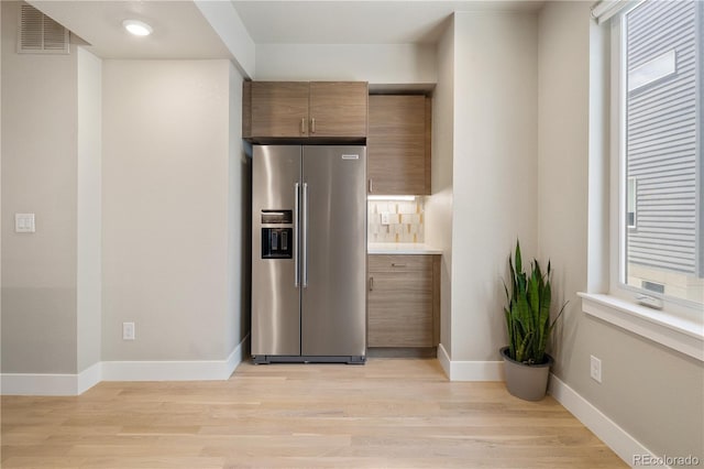 kitchen with baseboards, stainless steel refrigerator with ice dispenser, visible vents, and light wood-style flooring