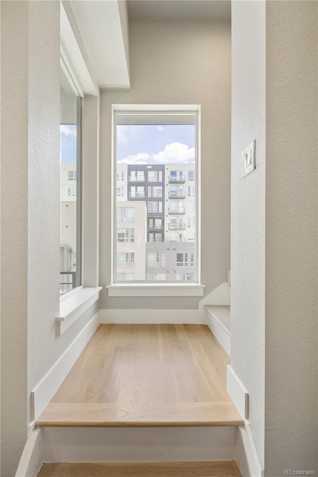 interior space featuring baseboards, a textured wall, and wood finished floors