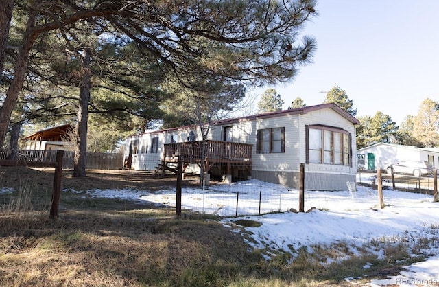 snow covered house with a wooden deck