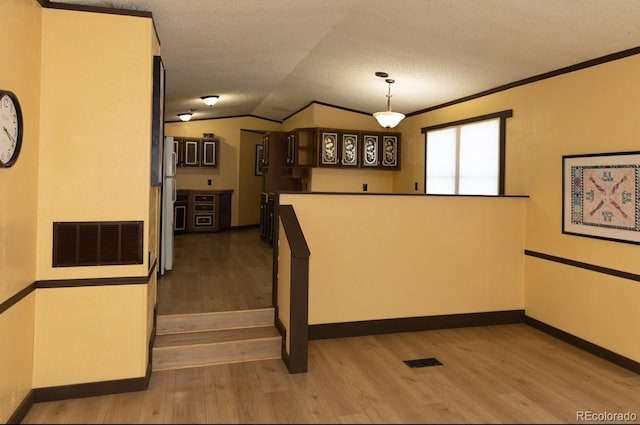 staircase featuring hardwood / wood-style floors, a textured ceiling, vaulted ceiling, and crown molding