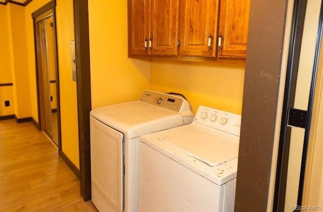 laundry room featuring cabinets, washing machine and dryer, and light hardwood / wood-style flooring