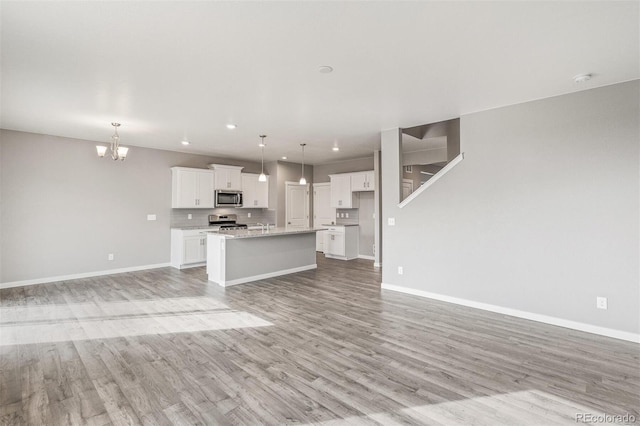 13466 Valentia St, Thornton, CO 80602 - unfurnished living room with a chandelier, light wood-type flooring, baseboards, and recessed lighting