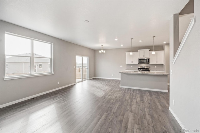 13466 Valentia St, Thornton, CO 80602 - unfurnished living room featuring dark wood-style floors, recessed lighting, a chandelier, and baseboards