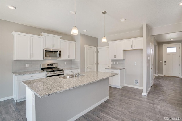 13466 Valentia St, Thornton, CO 80602 - kitchen with appliances with stainless steel finishes, a sink, backsplash, a kitchen island with sink, and light wood-style flooring