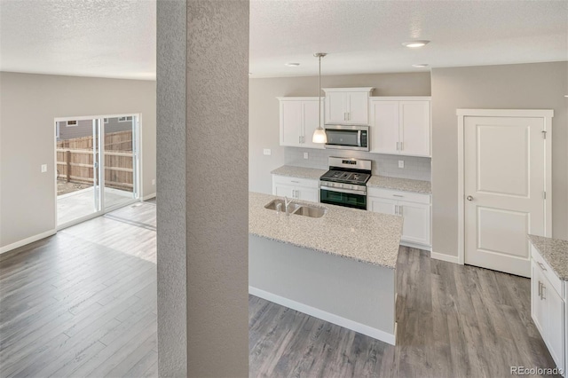 13466 Valentia St, Thornton, CO 80602 - kitchen with appliances with stainless steel finishes, wood finished floors, a sink, decorative backsplash, and a textured ceiling