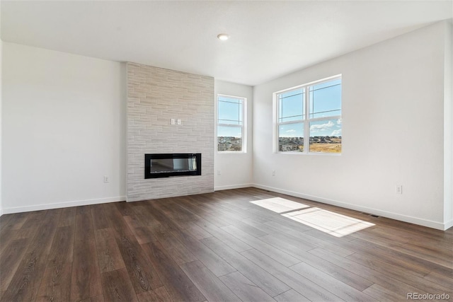 unfurnished living room featuring dark wood-type flooring and a fireplace