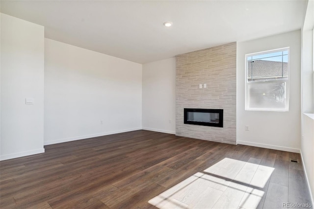 unfurnished living room featuring a large fireplace and dark hardwood / wood-style floors