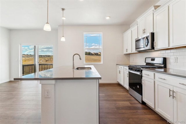 kitchen with a center island with sink, stainless steel appliances, hanging light fixtures, and sink