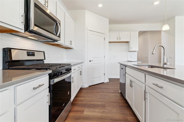 kitchen with white cabinets, stainless steel appliances, decorative light fixtures, and dark hardwood / wood-style flooring