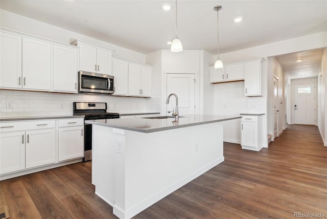 kitchen with a center island with sink, stainless steel appliances, dark hardwood / wood-style floors, sink, and white cabinets