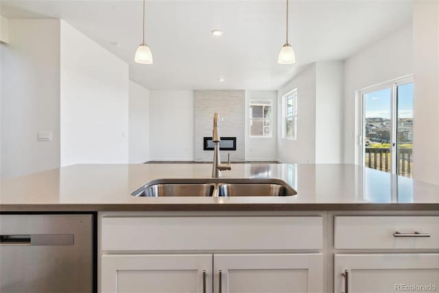 kitchen featuring dishwasher, sink, pendant lighting, and white cabinets