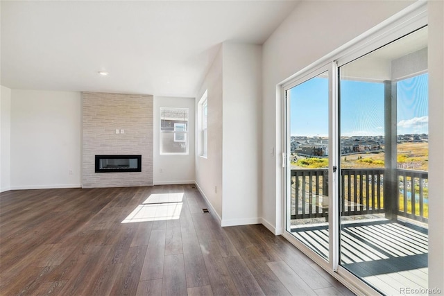 unfurnished living room featuring a large fireplace and dark hardwood / wood-style flooring