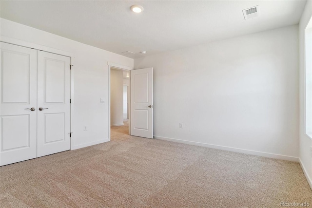 unfurnished bedroom with light carpet and a closet