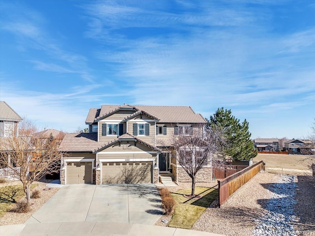 view of front facade featuring driveway, stone siding, a tile roof, fence, and roof mounted solar panels