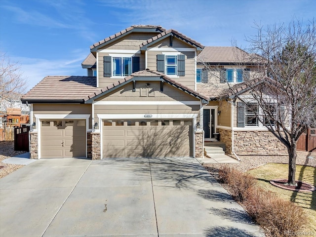 craftsman-style house featuring a tile roof, fence, a garage, stone siding, and driveway