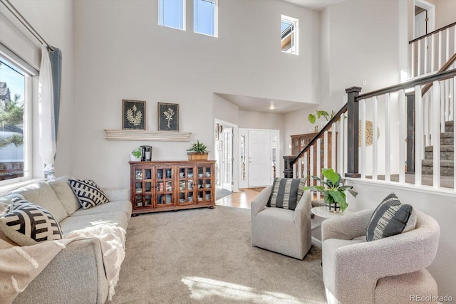 carpeted living room with a healthy amount of sunlight, stairs, and a high ceiling