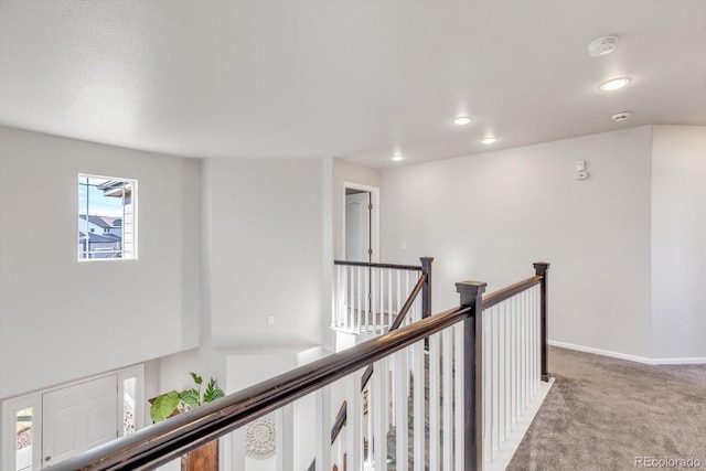 hall with carpet, baseboards, an upstairs landing, and recessed lighting