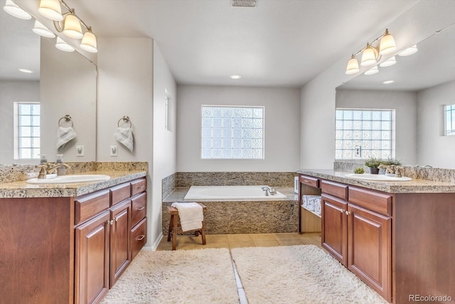 full bathroom with two vanities, a sink, and a bath