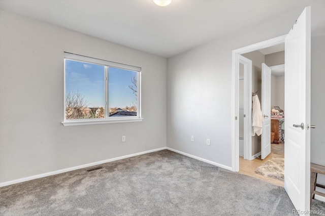 unfurnished room with carpet flooring, visible vents, and baseboards