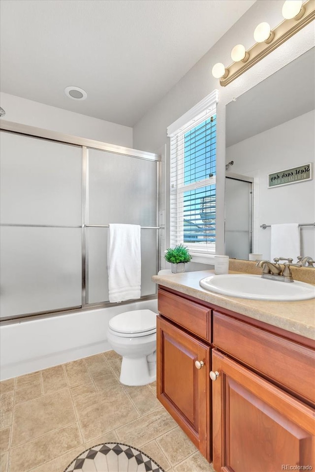 bathroom with shower / bath combination with glass door, vanity, toilet, and tile patterned floors