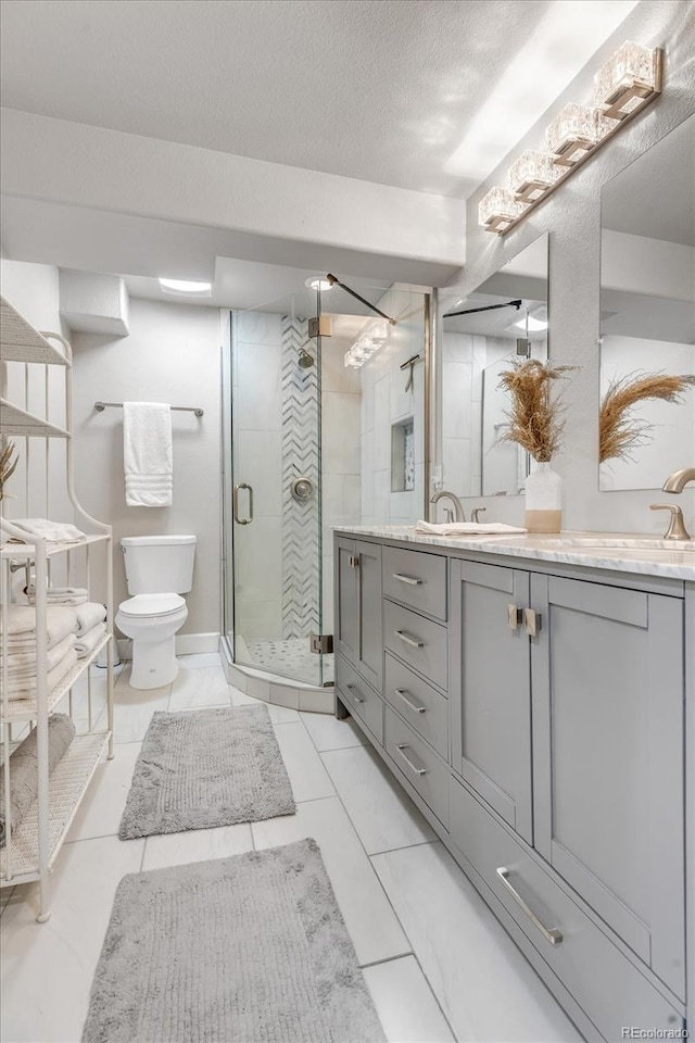 bathroom with toilet, a shower stall, a textured ceiling, and vanity