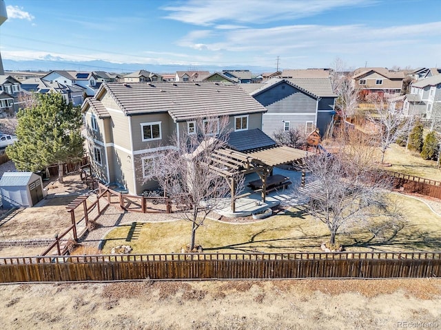 back of property with a tile roof, a residential view, and a fenced backyard