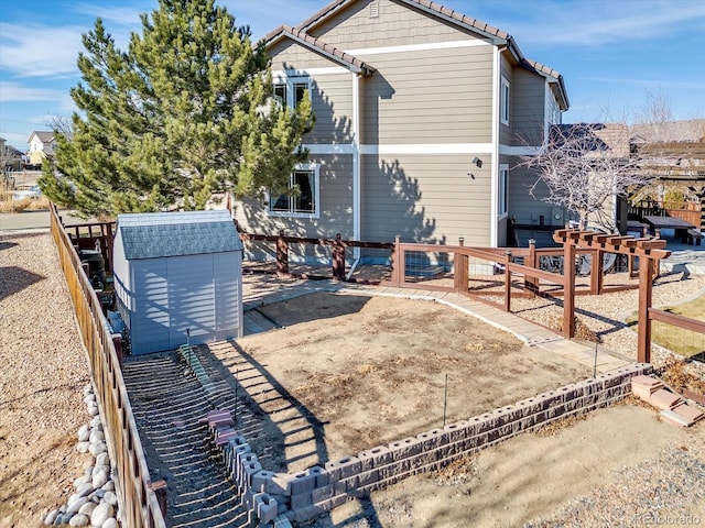 back of house featuring fence private yard, an outbuilding, and a storage unit