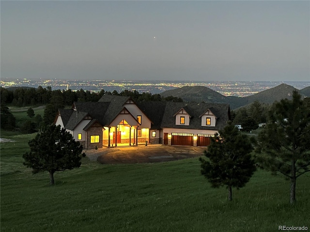 back house at dusk featuring a mountain view and a yard