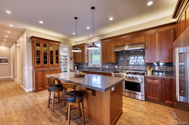 kitchen featuring sink, decorative light fixtures, a kitchen island, high end stainless steel range oven, and decorative backsplash