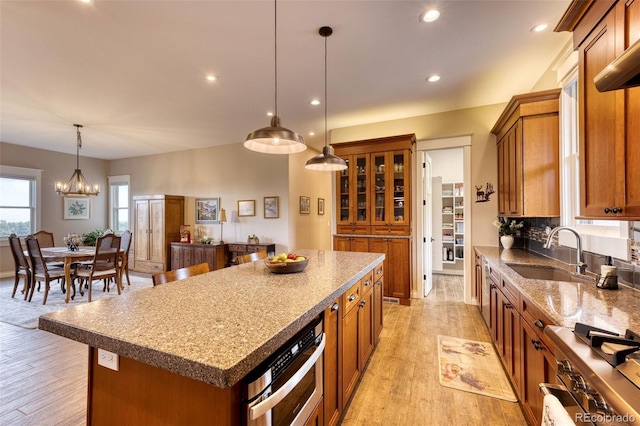 kitchen featuring sink, hanging light fixtures, light hardwood / wood-style flooring, appliances with stainless steel finishes, and a kitchen island