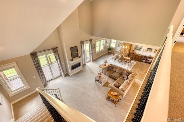 carpeted living room with an inviting chandelier and high vaulted ceiling