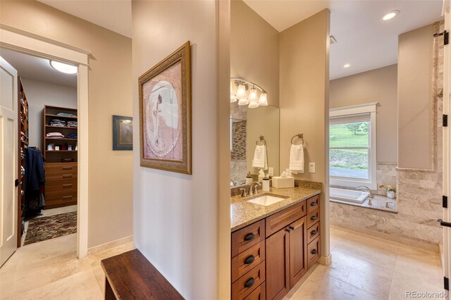 bathroom with tile patterned floors, vanity, and tiled bath