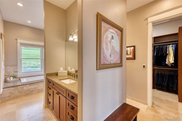 bathroom featuring tile patterned flooring, vanity, and a relaxing tiled tub