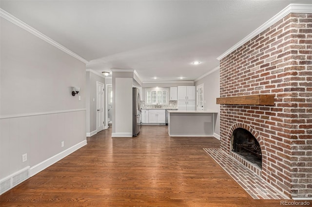 unfurnished living room with sink, ornamental molding, dark wood-type flooring, and a brick fireplace