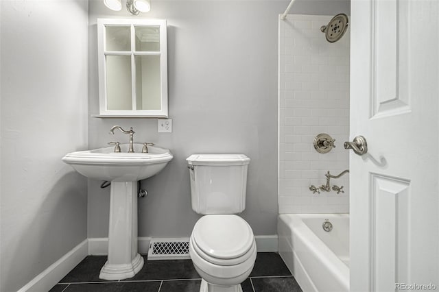 bathroom featuring tile patterned flooring, tiled shower / bath combo, and toilet