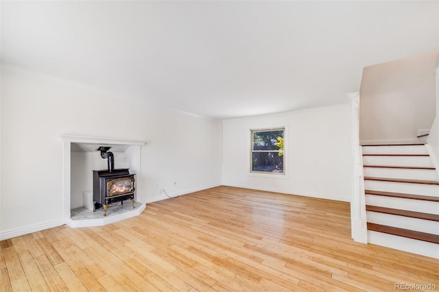 3870 S Ouray Way, Aurora, CO 80013 - unfurnished living room with a wood stove, light wood-style flooring, and stairway