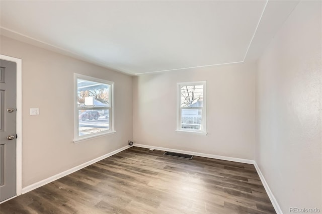 unfurnished room featuring a healthy amount of sunlight and dark hardwood / wood-style flooring