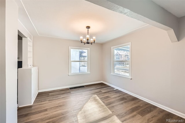 spare room with dark hardwood / wood-style floors and a notable chandelier