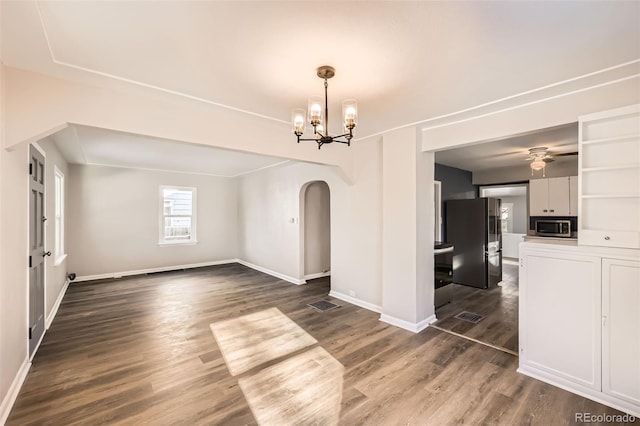 spare room featuring ceiling fan with notable chandelier and dark wood-type flooring