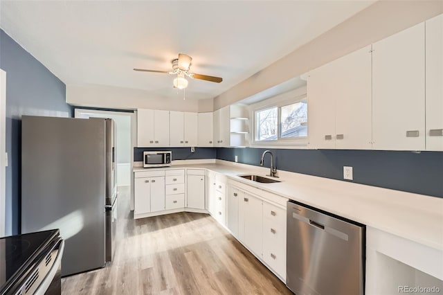 kitchen with white cabinetry, sink, ceiling fan, stainless steel appliances, and light hardwood / wood-style floors